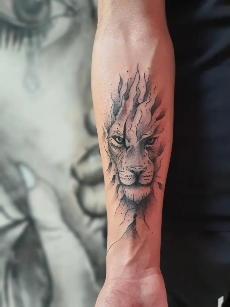 Ön koldaki siyah-gri sketch stili aslan yüzü dövmesi, yelesi alev gibi – Semih Art Tattoo, Bursa